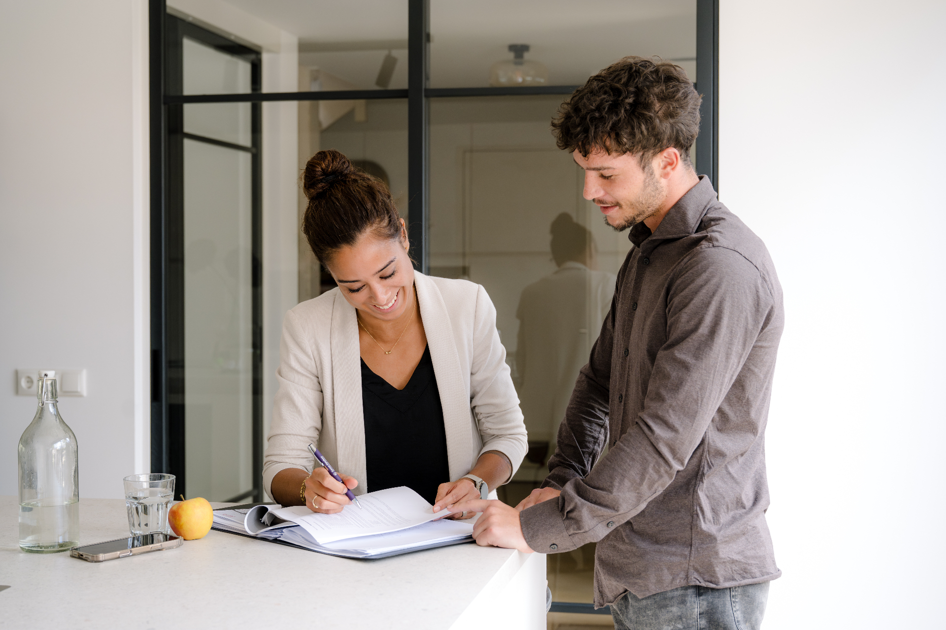 Twee collega's bespreken documenten in een lichte kantooromgeving